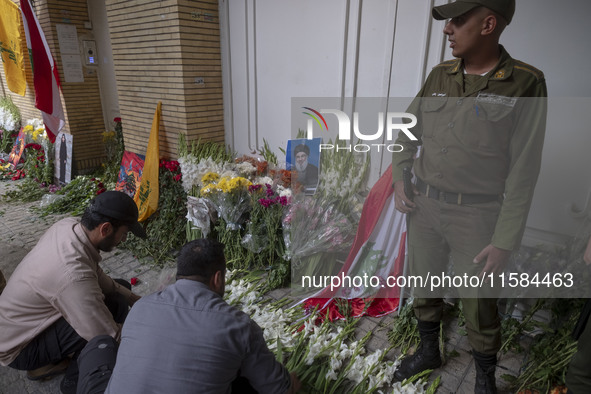 Two Iranian men place flowers as sympathy for victims of the deadly pager attack in Lebanon, in front of the Lebanese embassy in northern Te...