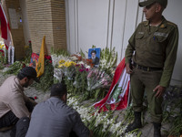 Two Iranian men place flowers as sympathy for victims of the deadly pager attack in Lebanon, in front of the Lebanese embassy in northern Te...