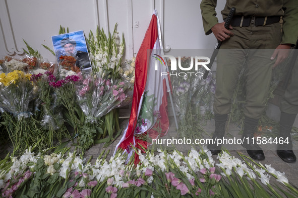 An Iranian policeman stands guard next to a portrait of Lebanon Hezbollah's Secretary-General Hassan Nasrallah and a Lebanese flag placed in...