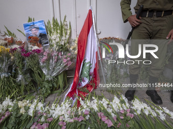 An Iranian policeman stands guard next to a portrait of Lebanon Hezbollah's Secretary-General Hassan Nasrallah and a Lebanese flag placed in...