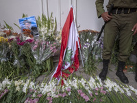 An Iranian policeman stands guard next to a portrait of Lebanon Hezbollah's Secretary-General Hassan Nasrallah and a Lebanese flag placed in...