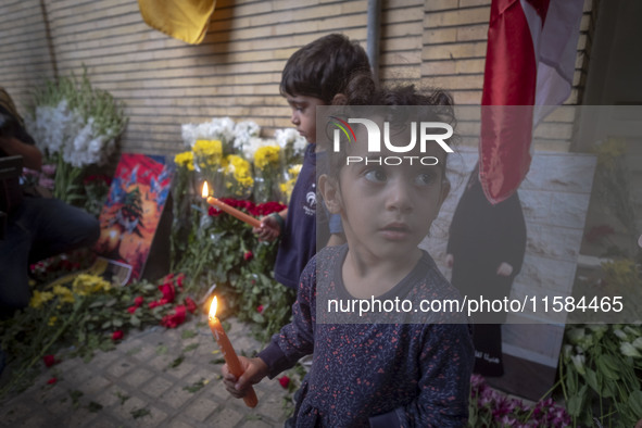 Iranian children hold candles while standing in front of the Lebanese embassy as a gesture of sympathy for victims of the deadly pager attac...