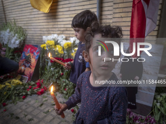 Iranian children hold candles while standing in front of the Lebanese embassy as a gesture of sympathy for victims of the deadly pager attac...