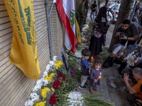 Iranian children hold candles next to a portrait of a young Lebanese girl who is killed in a deadly pager attack, while standing in front of...