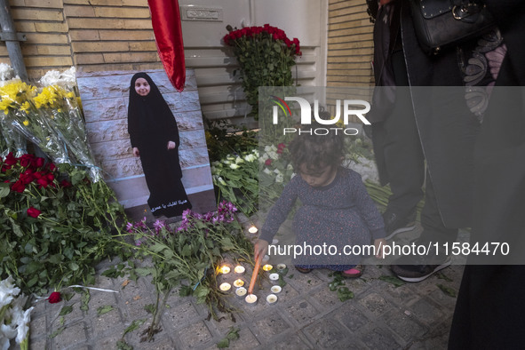 A young Iranian girl lights candles next to a portrait of a young Lebanese girl who is killed in a deadly pager attack in Lebanon, in front...