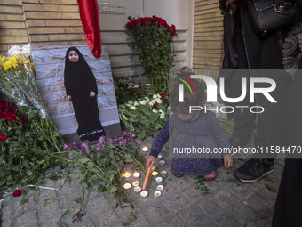 A young Iranian girl lights candles next to a portrait of a young Lebanese girl who is killed in a deadly pager attack in Lebanon, in front...