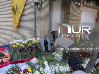 An Iranian man places flowers as sympathy for victims of the deadly pager attack in Lebanon, in front of the Lebanese embassy in northern Te...