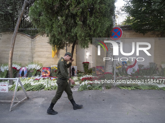 An Iranian soldier walks past flowers placed in front of the Lebanese embassy as a gesture of sympathy for victims of the deadly pager attac...