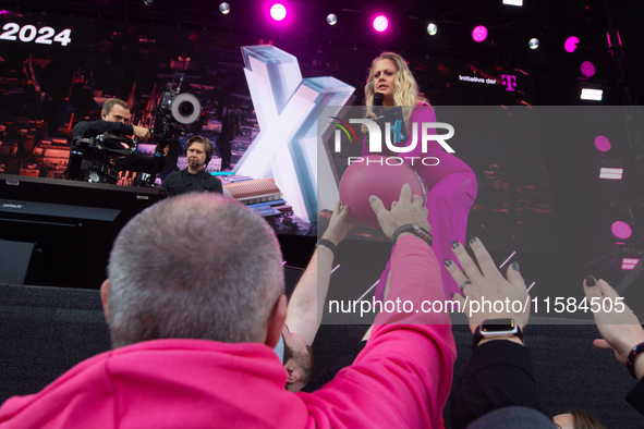 Barbara Schoneberger gives the helmet to people on the stage at Media Park on the opening day of Deutsche Telekom's Digital X event in Colog...