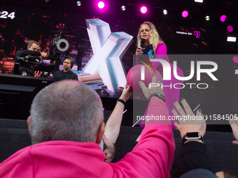 Barbara Schoneberger gives the helmet to people on the stage at Media Park on the opening day of Deutsche Telekom's Digital X event in Colog...