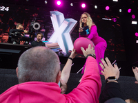 Barbara Schoneberger gives the helmet to people on the stage at Media Park on the opening day of Deutsche Telekom's Digital X event in Colog...