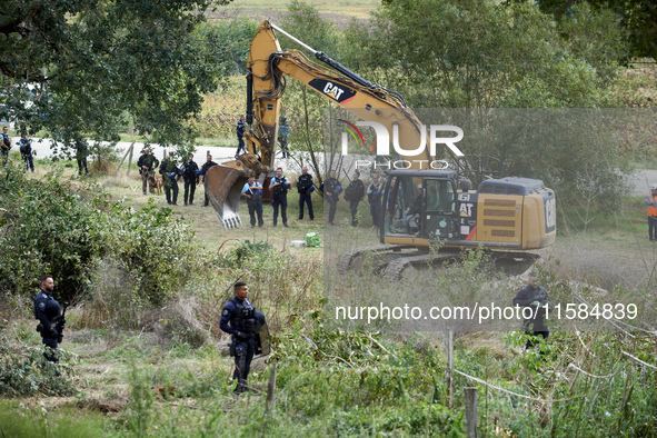 An excavator begins the work to destroy the 'Verger' ZAD as CNAMO policemen prepare to intervene to catch the people living in the tree on t...