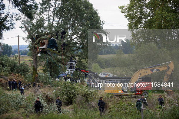 Access to the trees where the 'Ecureuil' (Squirrel) lives is blocked by policemen as workers from NGE wait to begin the destruction of the '...