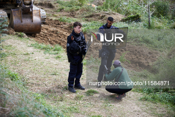 A protester films the excavator beginning to work as policemen are present. For the second day, Gendarmerie and CNAMO try to dislodge 'Ecure...