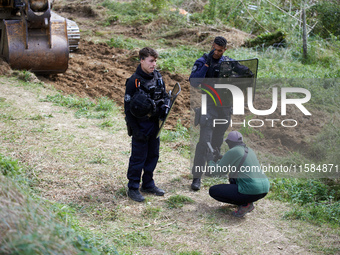 A protester films the excavator beginning to work as policemen are present. For the second day, Gendarmerie and CNAMO try to dislodge 'Ecure...