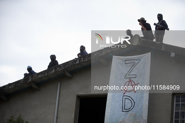 People stand on the roof of the 'Verger' house. The banner reads 'ZAD' (Zone to Defend). For the second day, Gendarmerie and CNAMO try to di...