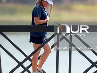 GAINESVILLE, VIRGINIA - SEPTEMBER 15: A standard bearer carries the sign on the bridge to the 12th tee for the score of Vice Captain Anna No...