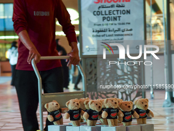 A volunteer carries teddy bears during the installation of ''Echo of Lost Innocence'' at the Barahat Mashaireb open-air gallery to draw atte...