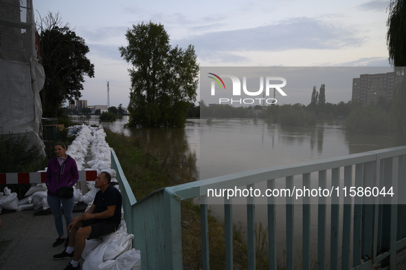 People sit by the Oder River in Olawa, near Wroclaw, Poland, on September 18, 2024. Emergency services, including fire departments and terri...