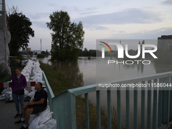 People sit by the Oder River in Olawa, near Wroclaw, Poland, on September 18, 2024. Emergency services, including fire departments and terri...