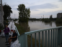 People sit by the Oder River in Olawa, near Wroclaw, Poland, on September 18, 2024. Emergency services, including fire departments and terri...