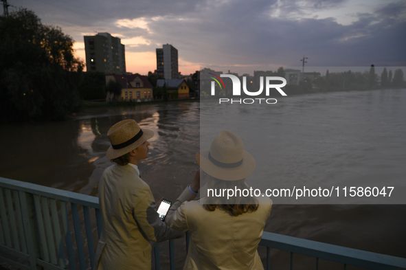 People on a bridge look at the high water level in the Oder river in Olawa, near Wroclaw, Poland, on September 18, 2024. Emergency services,...