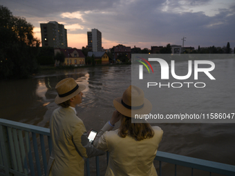 People on a bridge look at the high water level in the Oder river in Olawa, near Wroclaw, Poland, on September 18, 2024. Emergency services,...