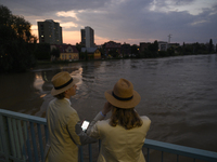 People on a bridge look at the high water level in the Oder river in Olawa, near Wroclaw, Poland, on September 18, 2024. Emergency services,...