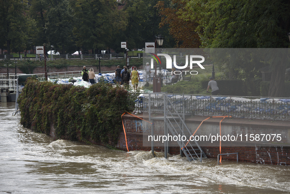 People walk next to sandbags during high waters in the Oder River in Wroclaw, Poland, on September 19, 2024. 