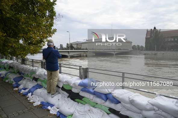 A man takes pictures as he stands on sandbags placed against the Oder river banks during high water in Wroclaw, Poland, on September 19, 202...