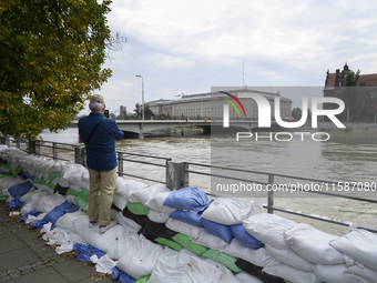 A man takes pictures as he stands on sandbags placed against the Oder river banks during high water in Wroclaw, Poland, on September 19, 202...