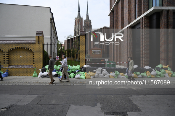 People walk next to sandbags during high waters in the Oder River in Wroclaw, Poland, on September 19, 2024. 