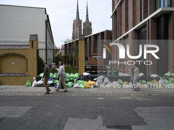 People walk next to sandbags during high waters in the Oder River in Wroclaw, Poland, on September 19, 2024. (