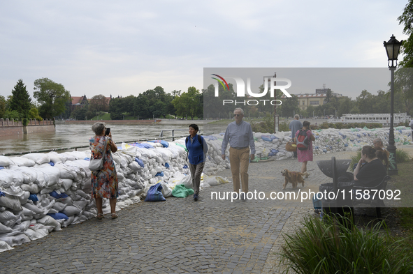 People walk next to sandbags during high waters in the Oder River in Wroclaw, Poland, on September 19, 2024. 