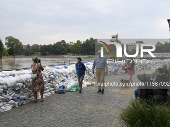 People walk next to sandbags during high waters in the Oder River in Wroclaw, Poland, on September 19, 2024. (