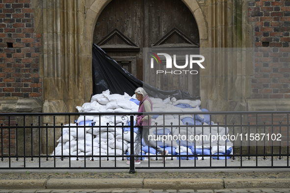 A woman walks past sandbags amassed against a church's door during high waters in the Oder River in Wroclaw, Poland, on September 19, 2024. 