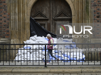 A woman walks past sandbags amassed against a church's door during high waters in the Oder River in Wroclaw, Poland, on September 19, 2024....