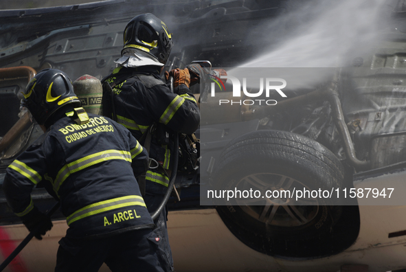 Members of the Heroic Fire Brigade put out fires in a car during the National Fire Drill 2024 in the Zocalo of Mexico City, Mexico, on Septe...