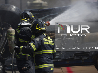 Members of the Heroic Fire Brigade put out fires in a car during the National Fire Drill 2024 in the Zocalo of Mexico City, Mexico, on Septe...