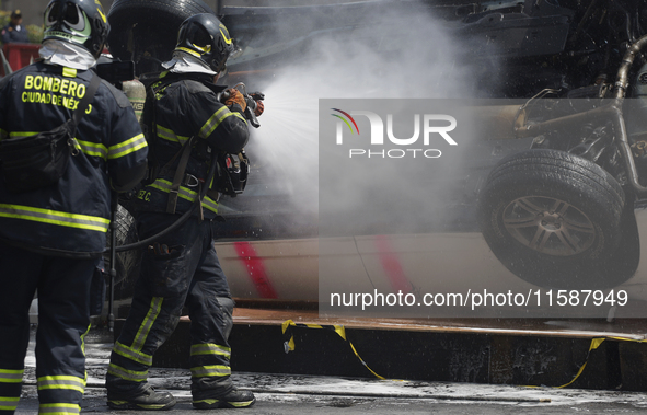 Members of the Heroic Fire Brigade put out fires in a car during the National Fire Drill 2024 in the Zocalo of Mexico City, Mexico, on Septe...