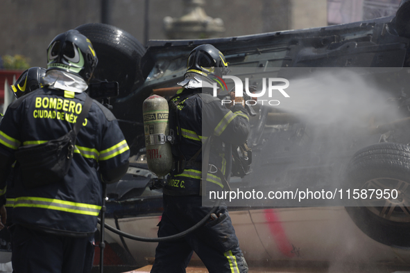 Members of the Heroic Fire Brigade put out fires in a car during the National Fire Drill 2024 in the Zocalo of Mexico City, Mexico, on Septe...