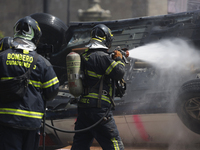 Members of the Heroic Fire Brigade put out fires in a car during the National Fire Drill 2024 in the Zocalo of Mexico City, Mexico, on Septe...