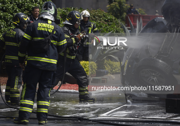 Members of the Heroic Fire Brigade put out fires in a car during the National Fire Drill 2024 in the Zocalo of Mexico City, Mexico, on Septe...