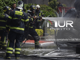 Members of the Heroic Fire Brigade put out fires in a car during the National Fire Drill 2024 in the Zocalo of Mexico City, Mexico, on Septe...