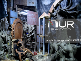 A boy takes his mobile phone in front of an idol of the Hindu goddess Durga in Kumartuli, the potter's village in Kolkata, India, on Septemb...