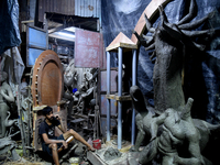 A boy takes his mobile phone in front of an idol of the Hindu goddess Durga in Kumartuli, the potter's village in Kolkata, India, on Septemb...