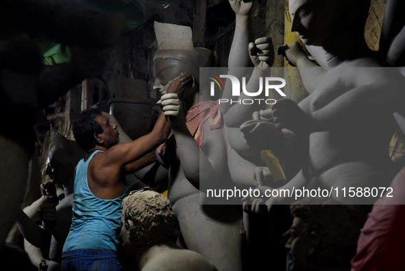 An artisan stands on a bamboo structure modeling the clay of a raw idol of goddess Durga inside his workshop in Kumartuli, Kolkata, India, o...