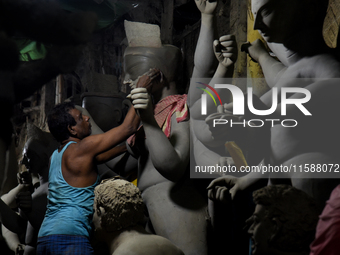 An artisan stands on a bamboo structure modeling the clay of a raw idol of goddess Durga inside his workshop in Kumartuli, Kolkata, India, o...