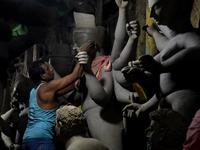 An artisan stands on a bamboo structure modeling the clay of a raw idol of goddess Durga inside his workshop in Kumartuli, Kolkata, India, o...