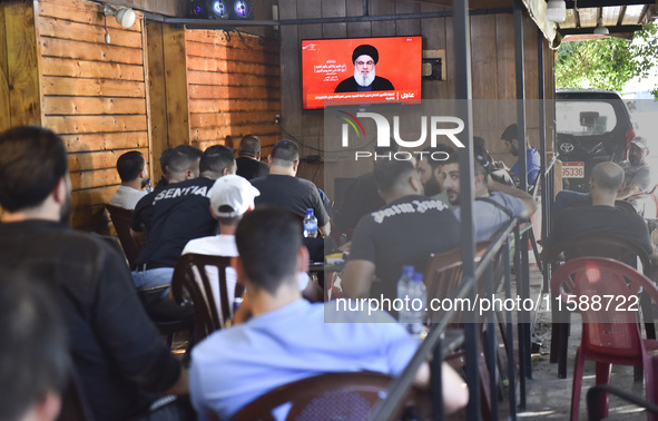 People watch Hezbollah leader Hassan Nasrallah on a television screen as he addresses the nation via video link at a cafe in the Shiyah neig...